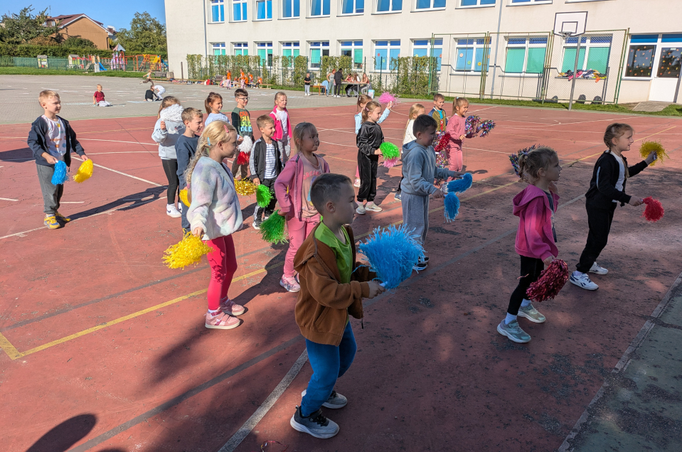 Dzieci tańczące z pomponami na boisku szkolnym