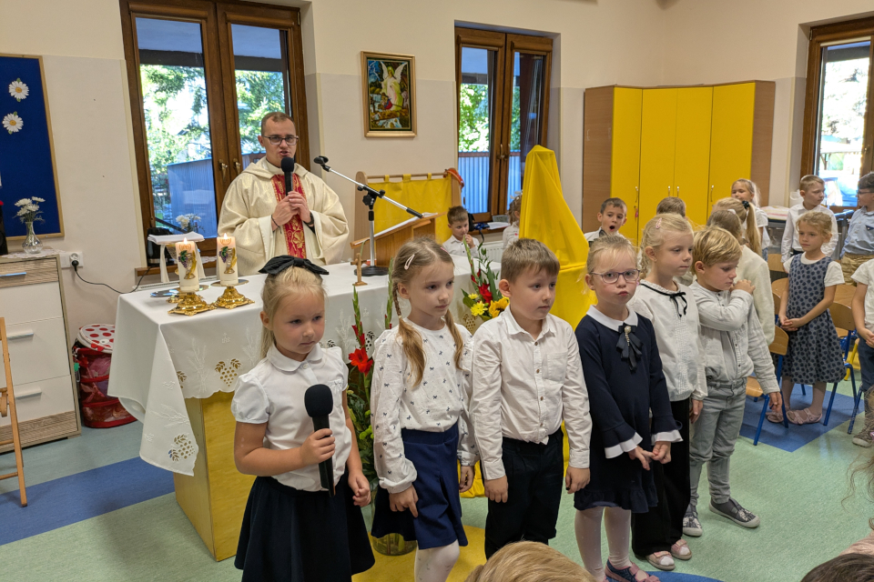 Dzieci stojące przed ołtarzem, za ołtarzem stoi ksiądz