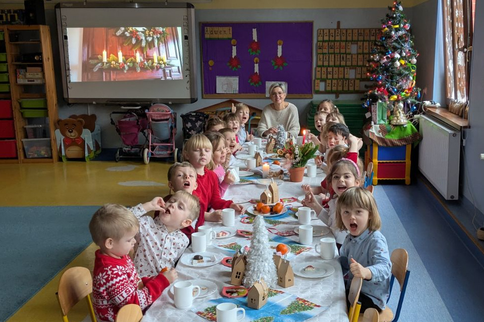 Dzieci siedzące przy wigilijnym stole wraz z nauczycielem