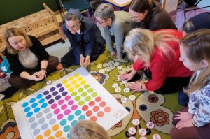 Nauczyciele siedzący na dywanie wokół maty do kodowania