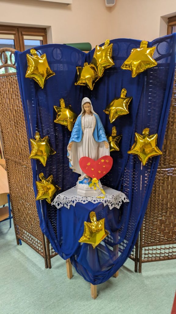 Figurka Maryi, pod nią serce z odciśniętymi paluszkami dzieci
