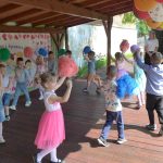 Dzieci tańczą w kole z pomponami