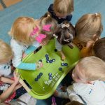 Dzieci łowiące za pomocą szczypców kulki z wanienki z wodą