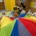 Dzieci wachlujące chustą animacyjną na której są kółka z papieru