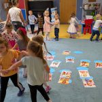 dzieci na dywanie tańczą wśród ilustracji świętych