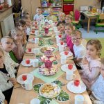 dzieci siedzą przy uroczystym posiłku