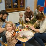 Rodzice wraz z dziećmi robią stroiki świąteczne.